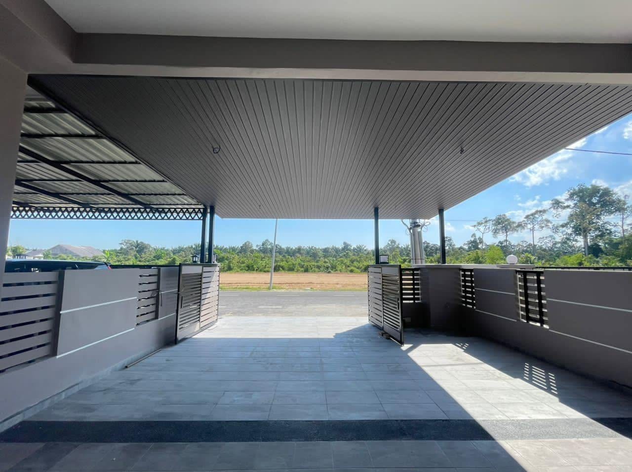 Looking out from under the porch roof: pale grey slatted ceiling, dark steel posts, grey and charcoal floor tiles, open slatted gates and a palm treeline.